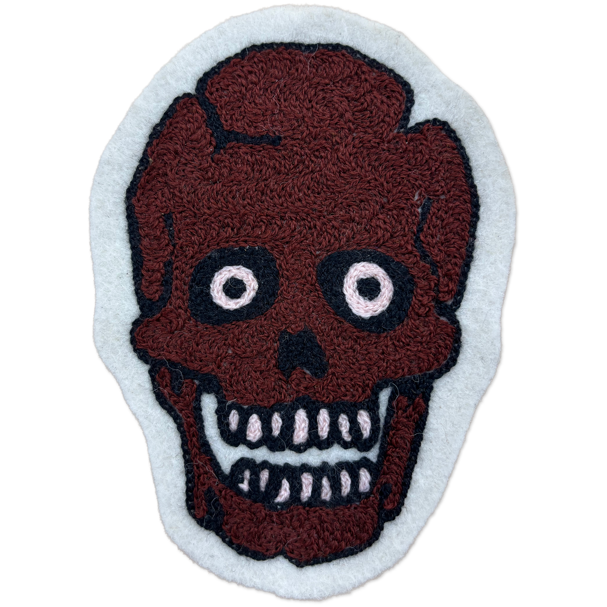 A handcrafted chainstitch patch featuring a stylized skull with a dark reddish-brown textured face, black outlines, and white details, set against a light gray background.
