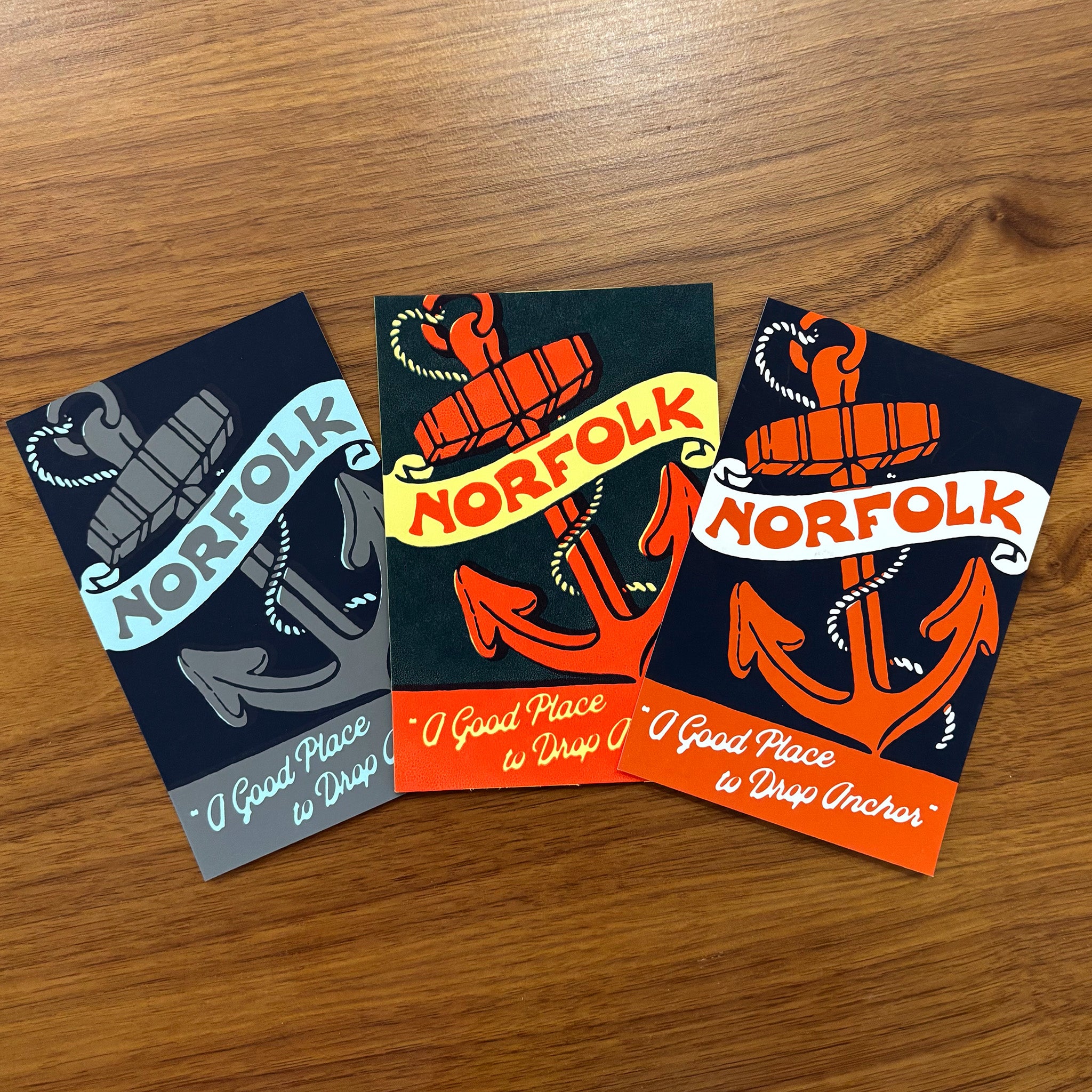 Three Norfolk-themed cards with anchors on a wooden surface