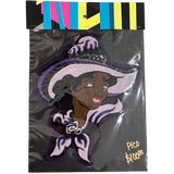 A packaged embroidered patch featuring a stylized witch character with a large lavender hat, dark hair, and purple trim, sealed in clear plastic with a colorful striped header card. Handwritten text in the corner reads 'Pico $100€'.
