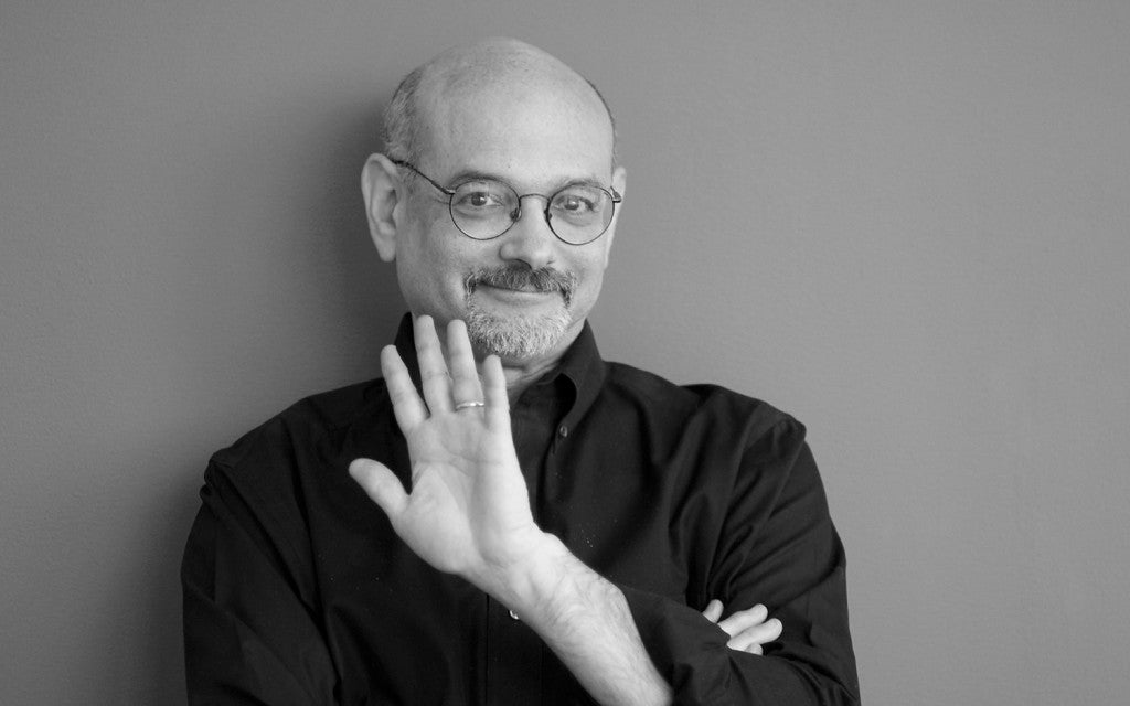 Man with glasses and a black shirt against a gray background
